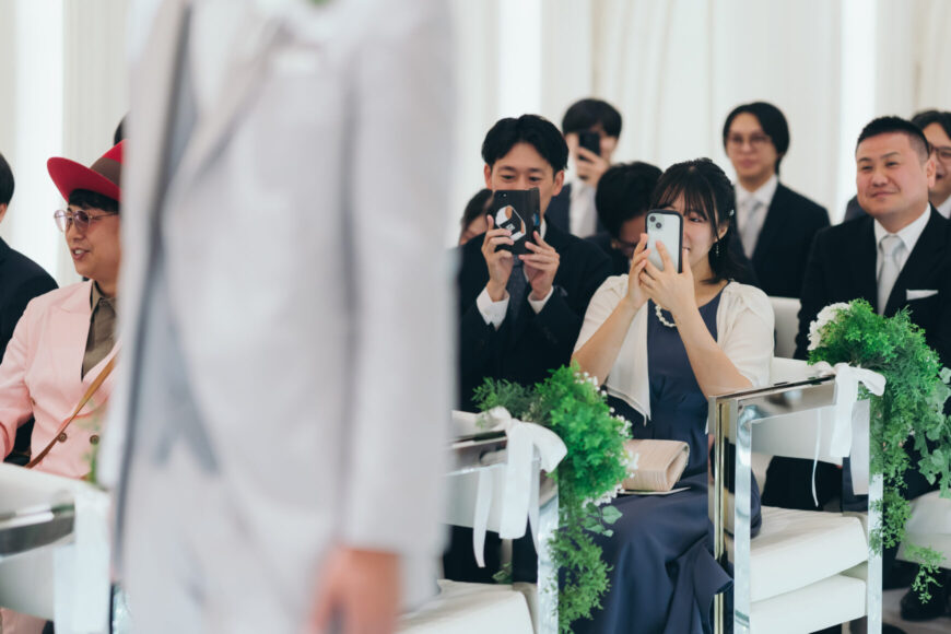 新郎の入場をスマートフォンで撮影するゲスト