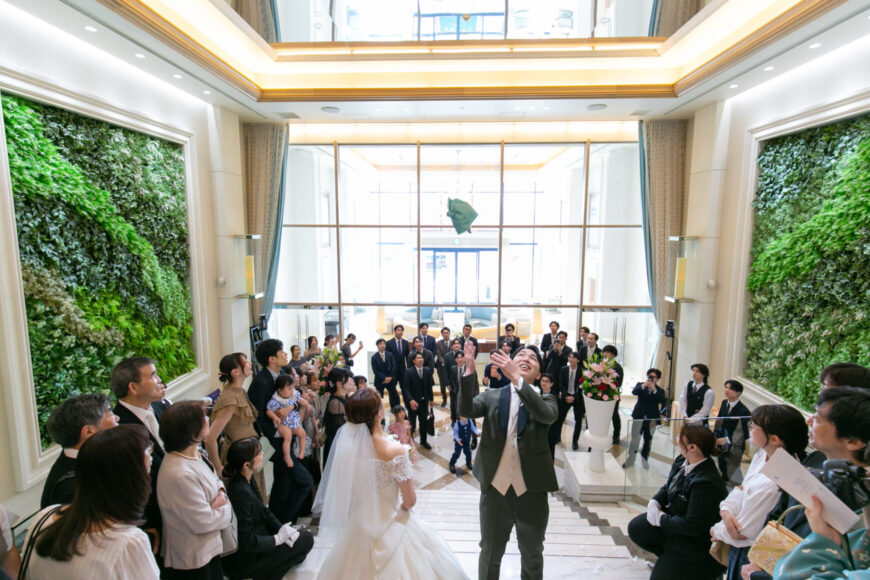 大階段の下でゲストに囲まれる新郎新婦