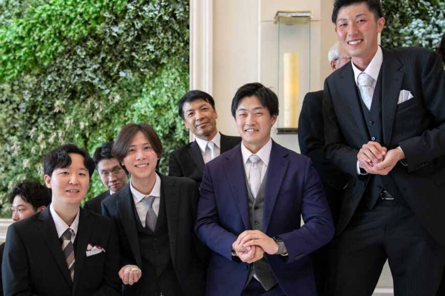 グリーンの壁の前で並ぶ新郎のご友人