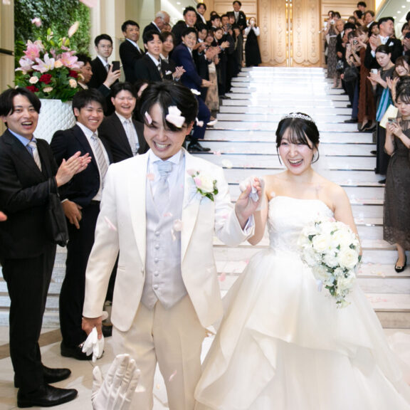 フラワーシャワーの中を笑顔で歩く新郎新婦