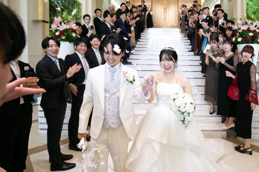 フラワーシャワーの中を笑顔で歩く新郎新婦