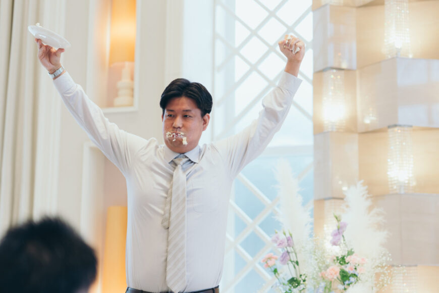 ケーキを頬張り両手を上げて喜ぶご友人