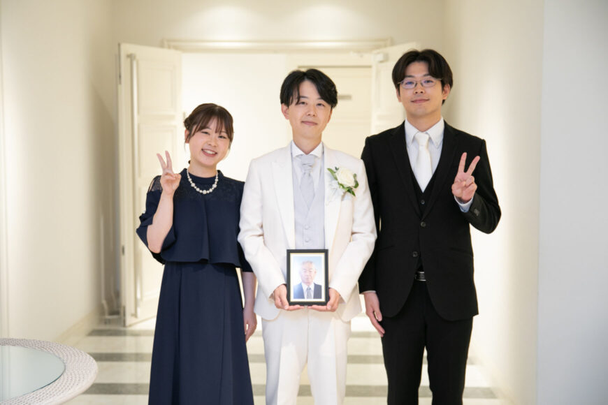 大切な写真を手にご家族と記念撮影する新郎